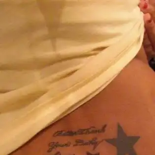 Cursive Text with Large Black Star and Small Red Star Tattoo
