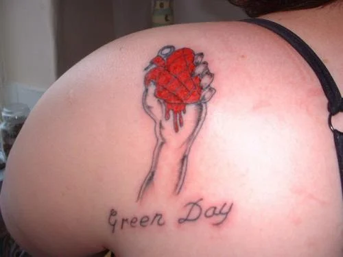 Hand Holding Anatomical Heart with Green Day Text Tattoo