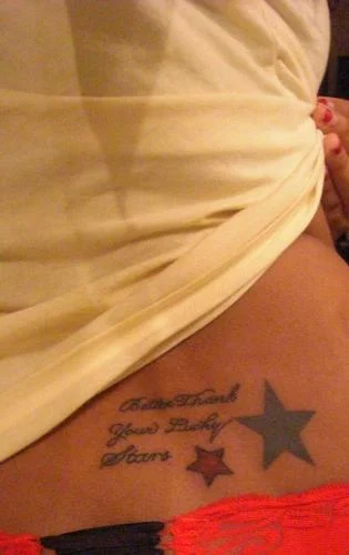 Cursive Text with Large Black Star and Small Red Star Tattoo